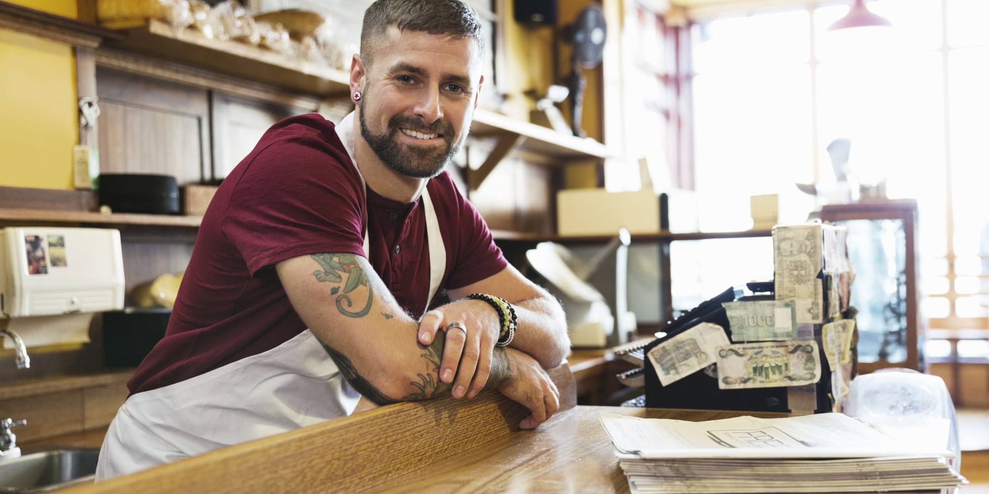 Portrait of male deli owner leaning on counter